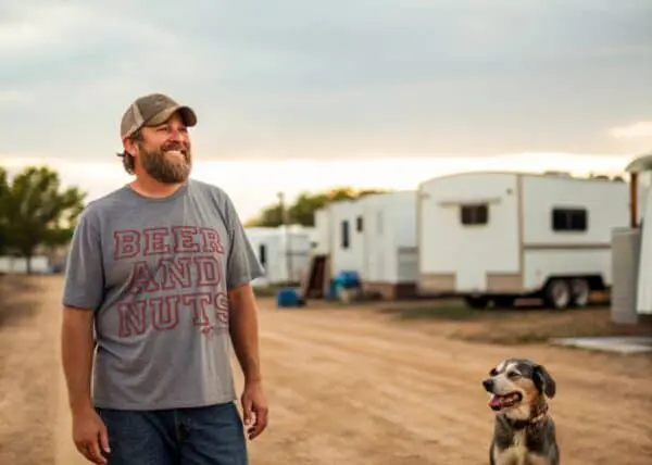 Happy man standing with his dog at campground with RV trailers.
