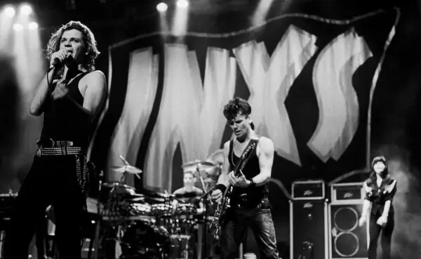 Dynamic black and white image of a live rock band with singer, guitarist, and drummer in action.