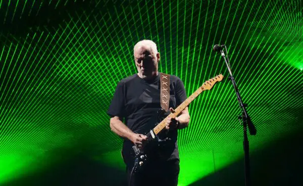A guitarist playing passionately on stage with green laser light effects creating an electrifying concert atmosphere.