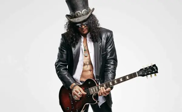 Musician wearing a top hat, sunglasses, and a leather jacket, playing an electric guitar.
