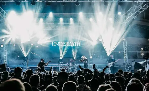 Underoath band performing on stage at a concert, vibrant lights, and enthusiastic crowd.