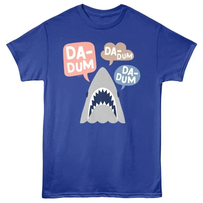 Bright blue T-shirt featuring a cartoon shark with speech bubbles saying "DADUM" for fun, trendy apparel.