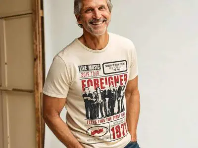 A smiling man wearing a vintage 1970s band tour t-shirt, showcasing retro style and music nostalgia.