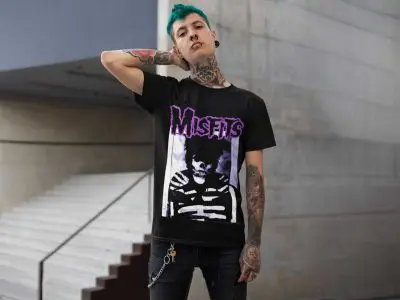 Bold punk style featuring a Misfits graphic T-shirt, tattoos, and teal hair, showcasing alternative fashion for fans of punk rock and edgy streetwear.