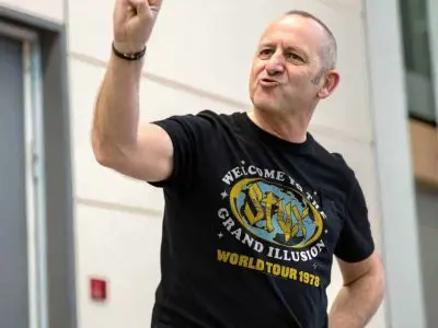 A man wearing a vintage Grateful Dead T-shirt making a rock and roll hand gesture at a concert or event.
