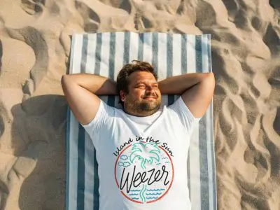 Relaxing man lying on a beach towel, enjoying sunshine in summer.