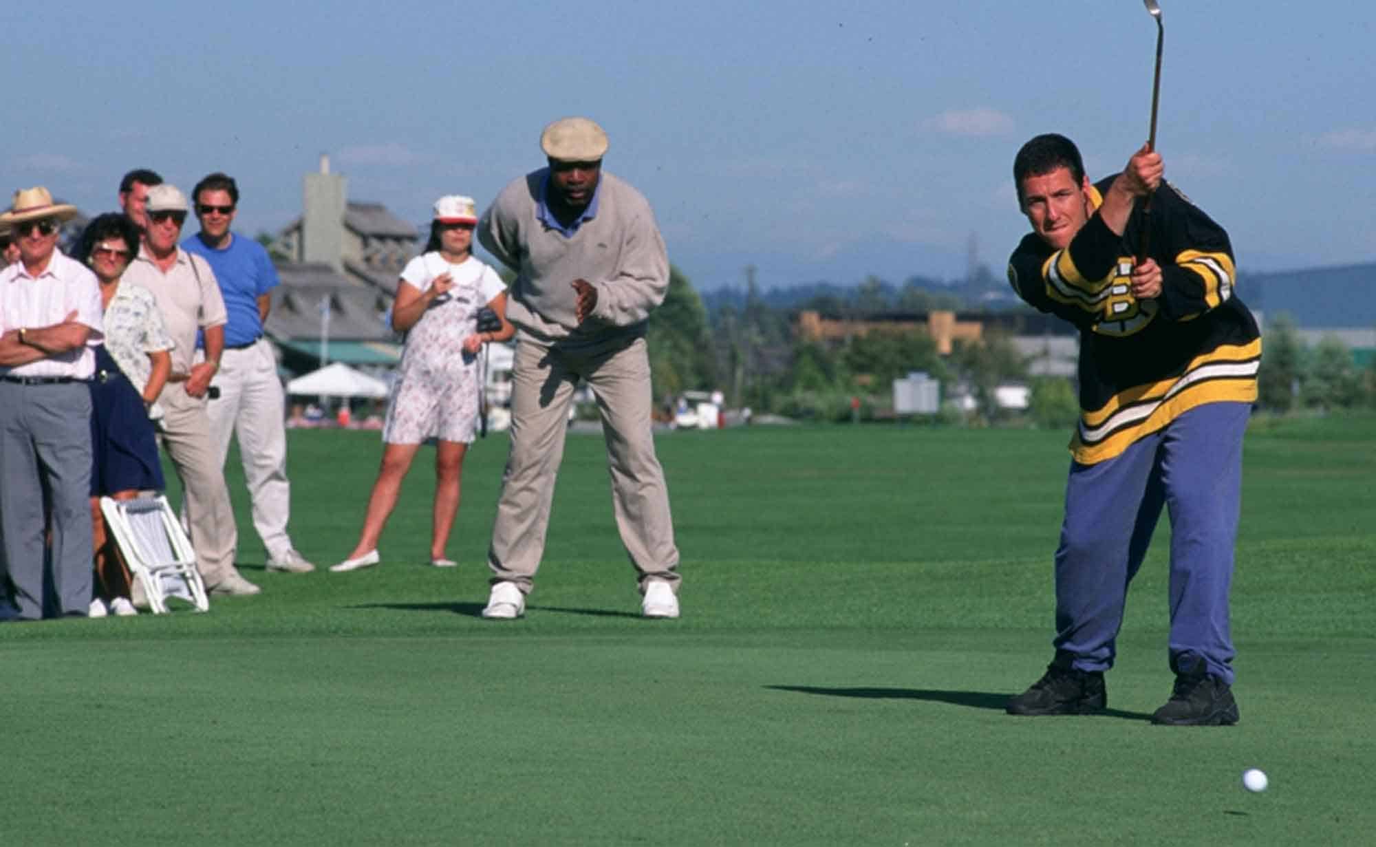 A group of people watching a golf game outdoors during a sunny day at a scenic golf course.