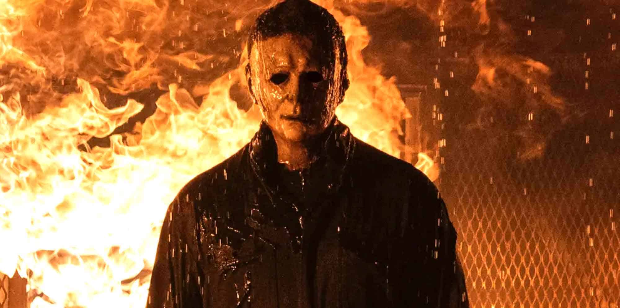 Eerie masked figure standing in front of flames, horror movie scene with intense fire backdrop.