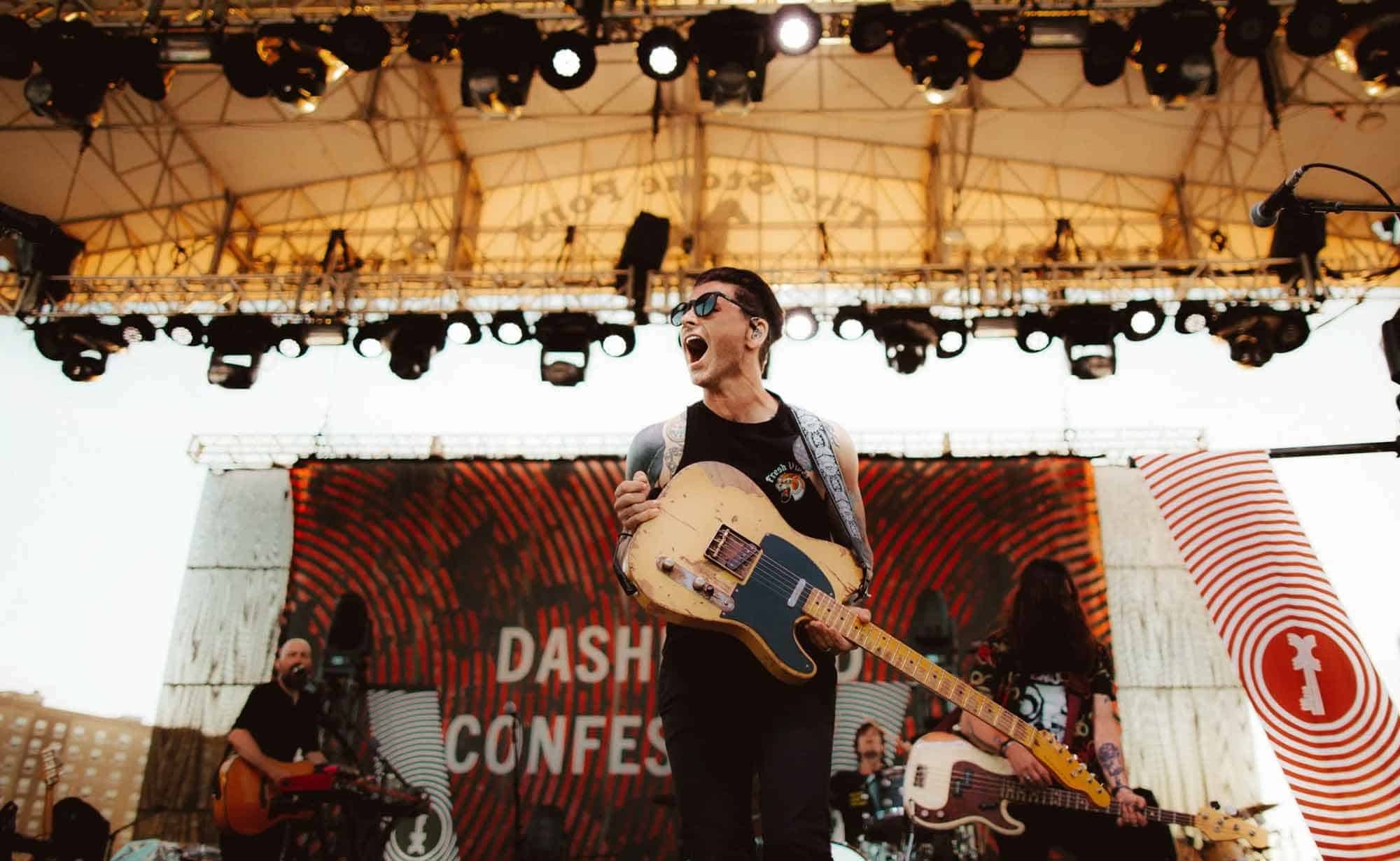 Vibrant outdoor concert scene with musicians performing passionately under stage lights.
