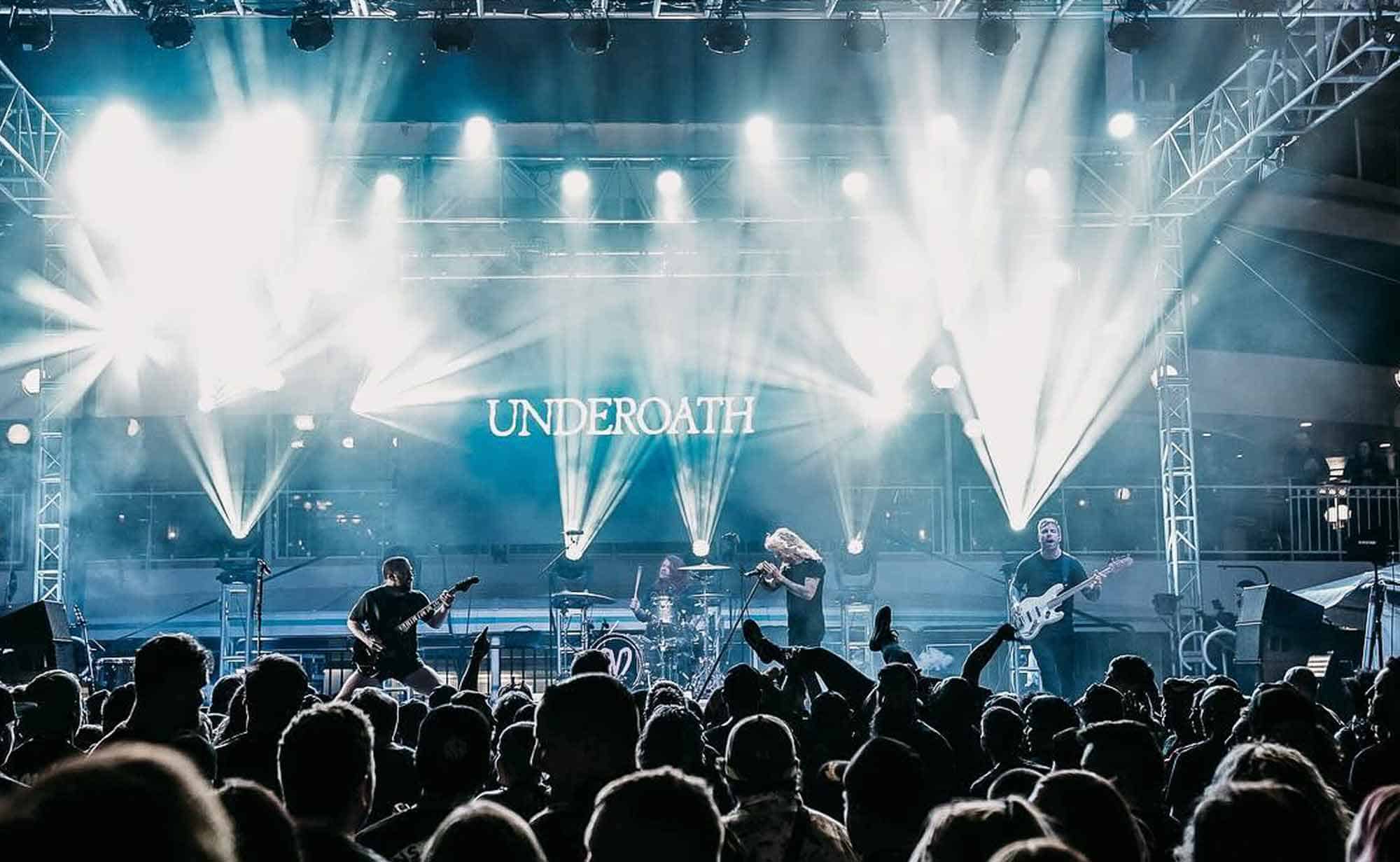 Underoath band performing on stage at a concert, vibrant lights, and enthusiastic crowd.