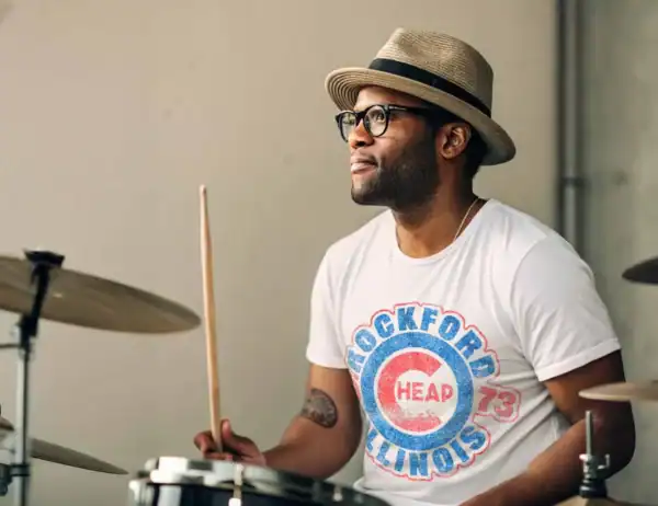 Man on a drum set wearing a Cheap Trick tee shirt