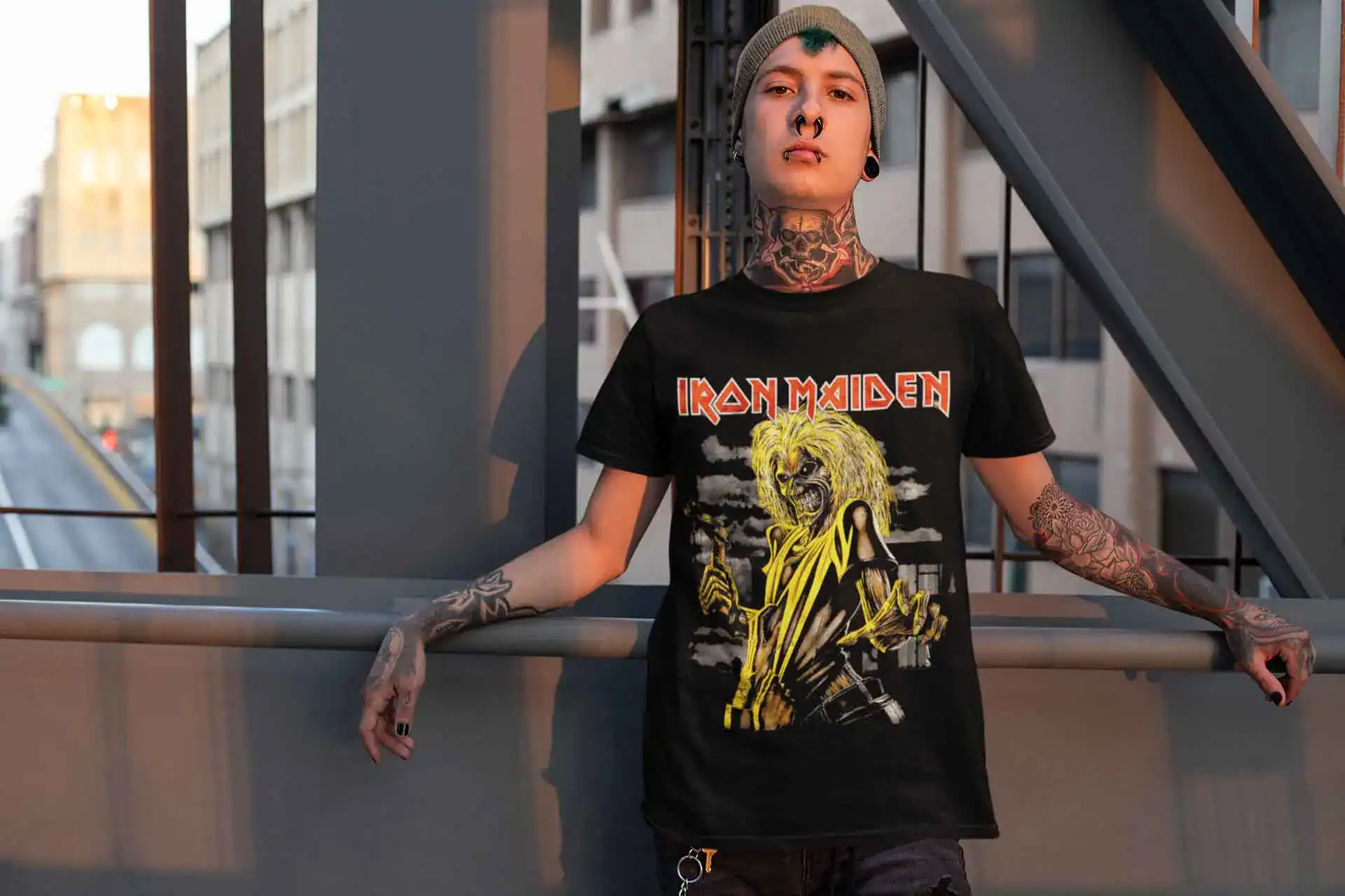 Bold punk rock style with an Iron Maiden graphic t-shirt, tattoos, and edgy accessories on an urban rooftop.