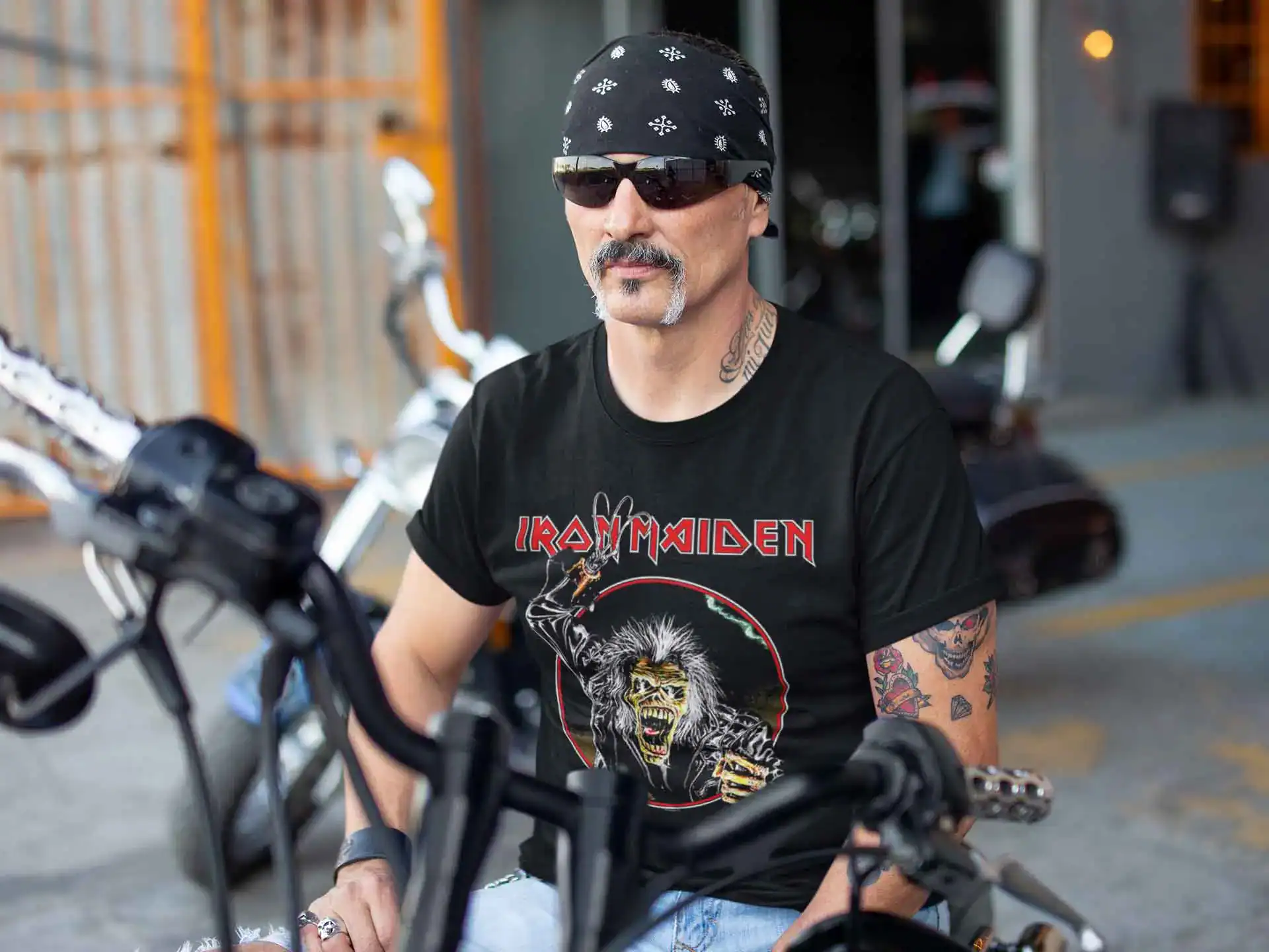 A stylish man wearing a bandana and Iron Maiden t-shirt, showcasing a cool rocker vibe sitting on a motorcycle