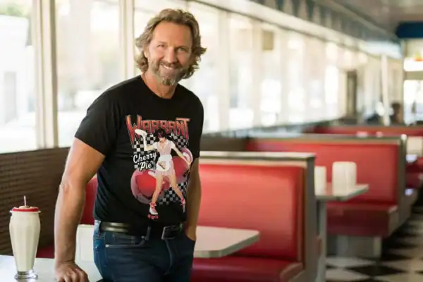 Relaxed man wearing graphic T-shirt in classic American diner setting, showcasing vintage ambiance and retro style.