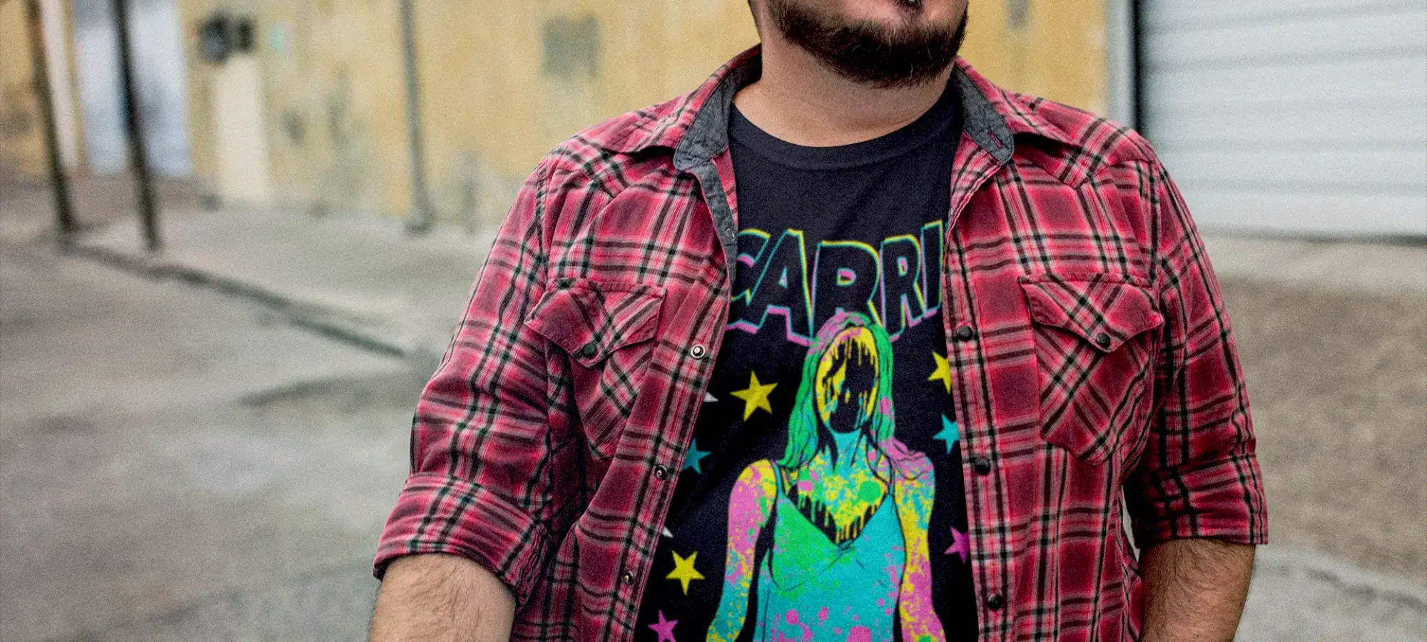 Colorful casual style featuring graphic T-shirt and plaid shirt in urban setting.