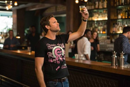 A man raising a glass at a bar, celebrating with friends, in a lively social scene, perfect for nightlife, party, and entertainment keywords.