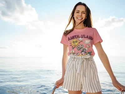 Bright woman smiling on a boat during sunny day at sea, wearing casual summer T-shirt and striped shorts.