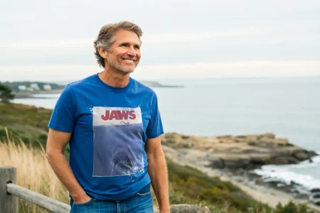 Portrait of a cheerful man wearing a Jaws movie T-shirt enjoying seaside scenery.
