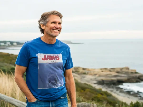 Portrait of a cheerful man wearing a Jaws movie T-shirt enjoying seaside scenery.