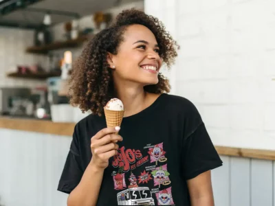 Smile, woman with curly hair enjoying ice cream in a trendy cafe.