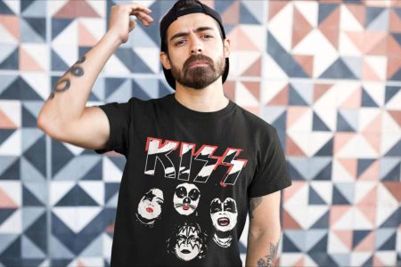 Striking young man with a beard in a black KISS band t-shirt standing in front of a vibrant geometric wall.