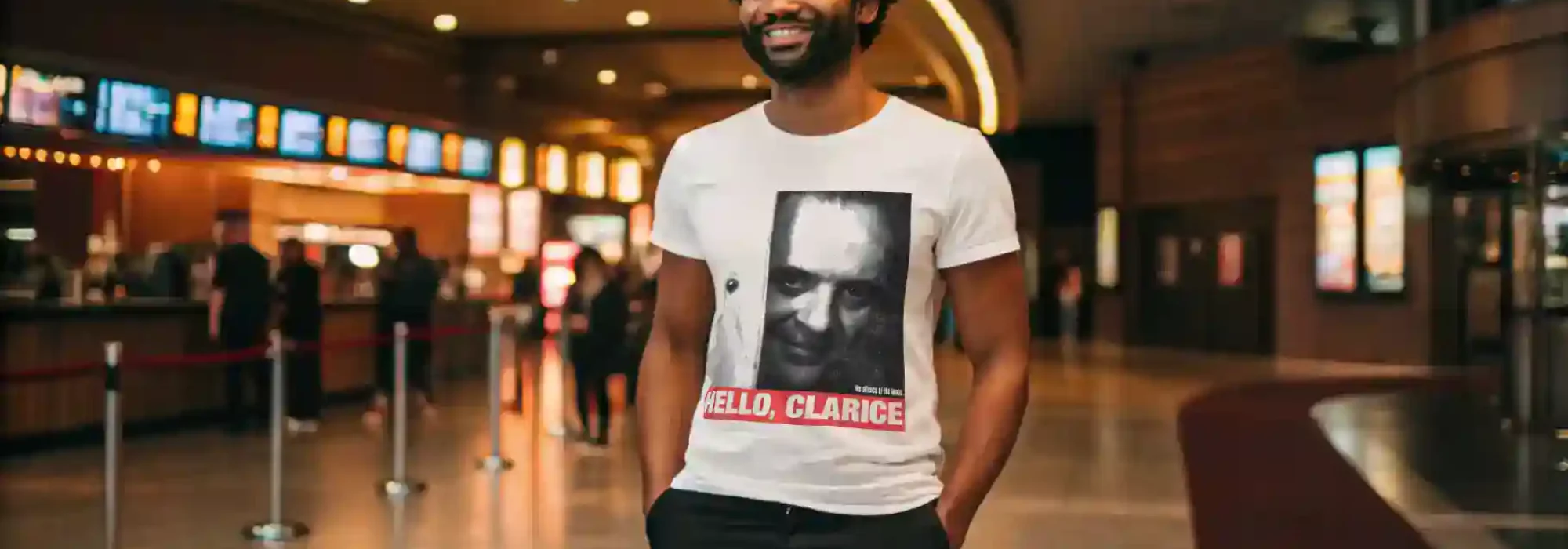 Picture of a smiling man in a graphic T-shirt at a cinema or entertainment venue.