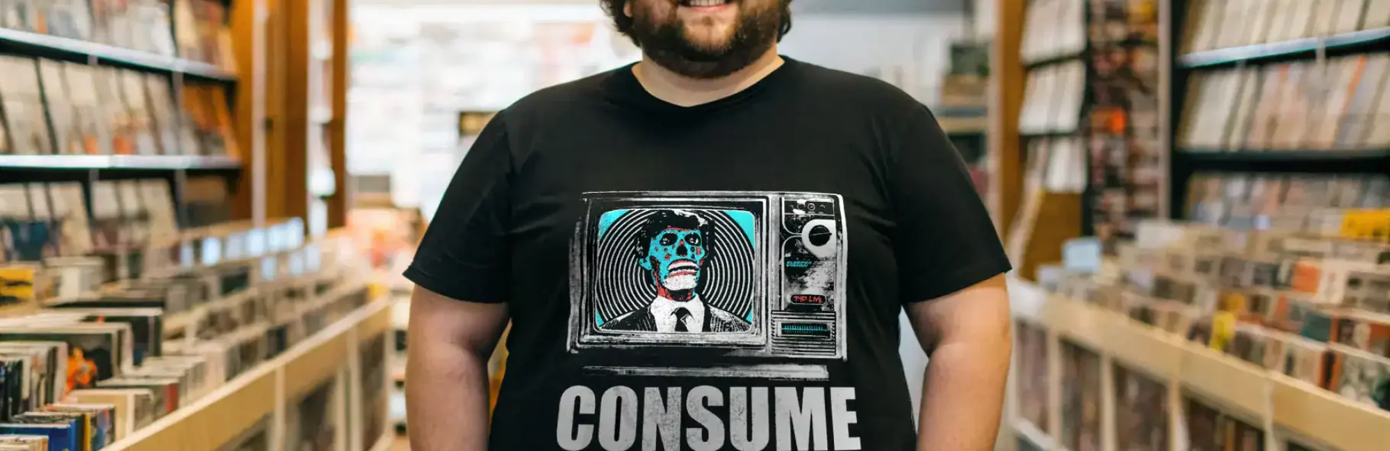 Men's pop culture T-shirt featuring skeleton TV graphic and "Consume" slogan, ideal for trendy fashion.