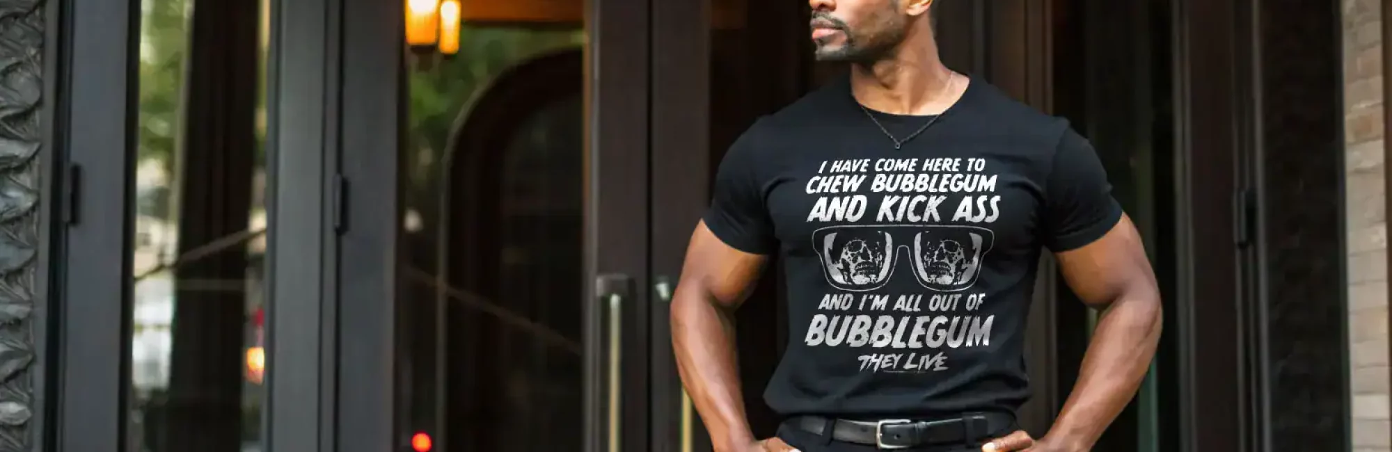 Man in black graphic t-shirt with humorous quote standing outside modern building.