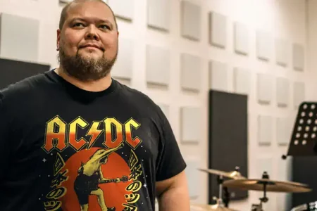 Music lover wearing AC/DC band t-shirt in professional recording studio environment.