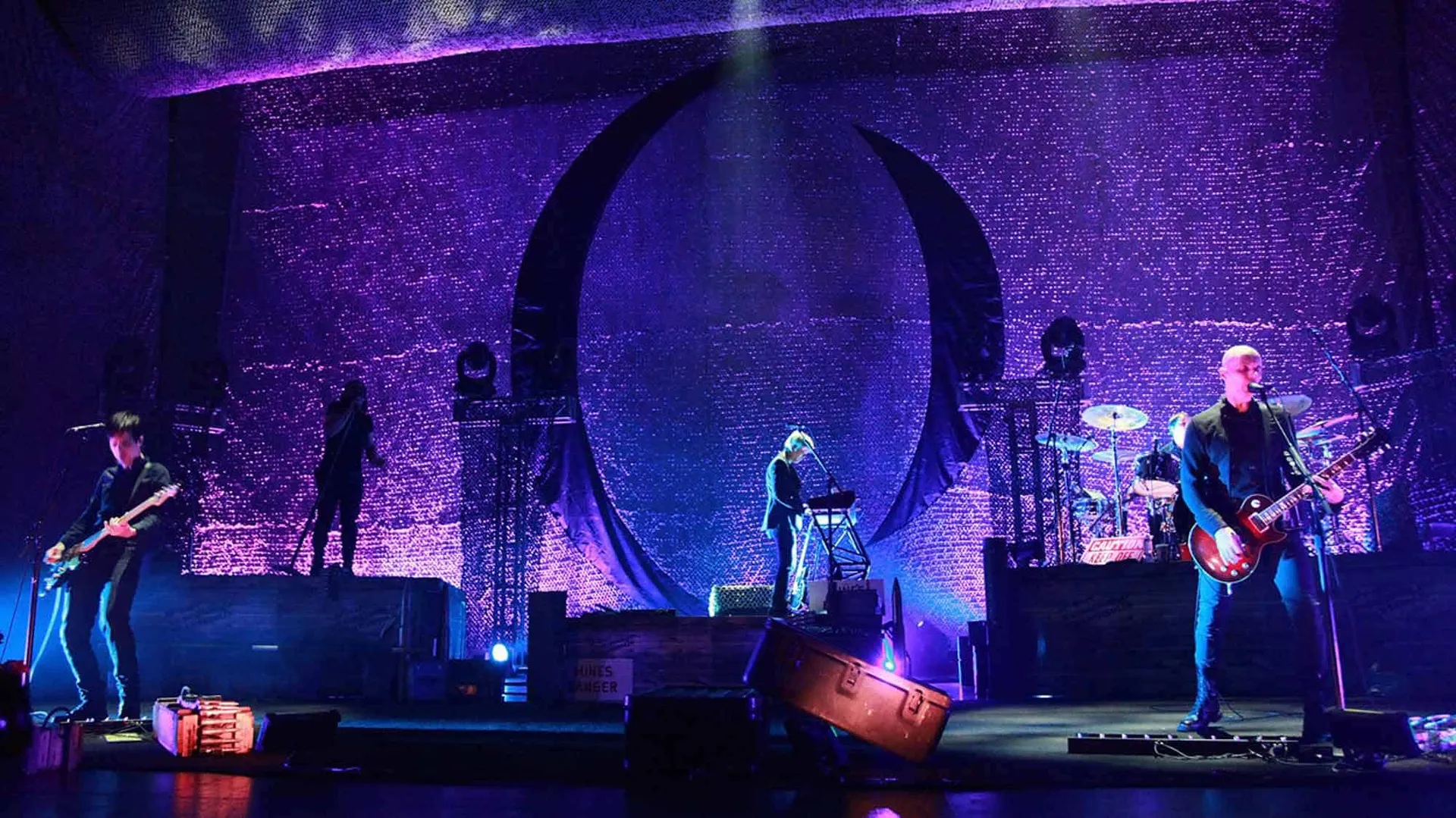 Colorful stage with musicians performing under purple LED lights, creating an energetic live music scene.