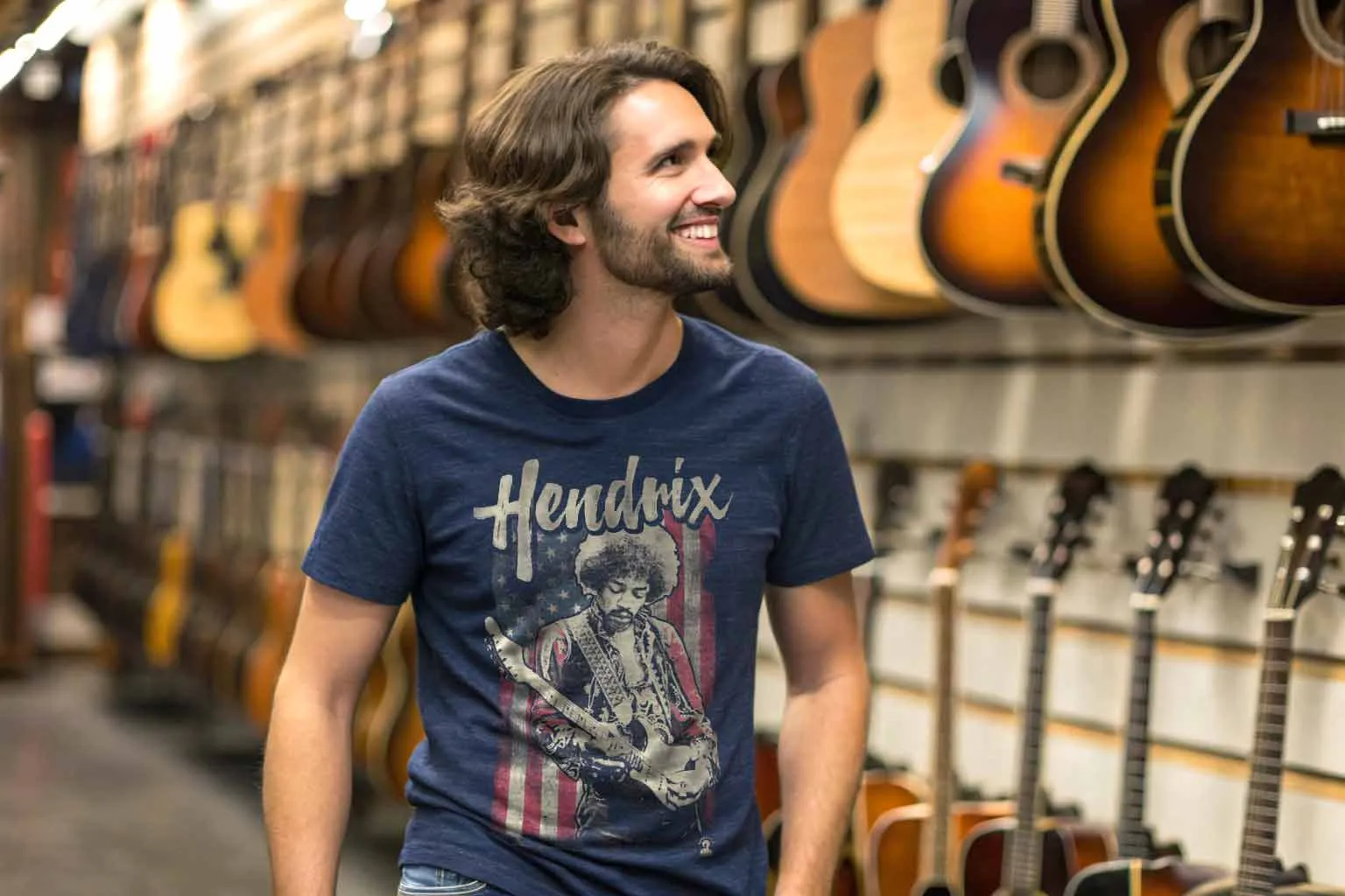 A smiling man browsing guitars in a musical instrument shop, featuring a variety of acoustic guitars hanging on display.