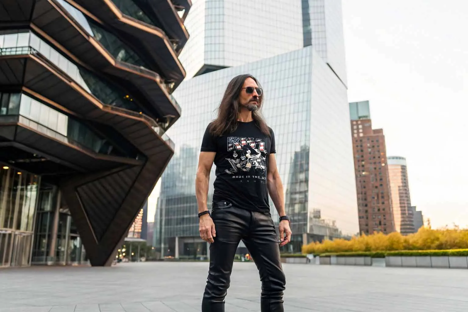 Man wearing rock band T-shirt with city buildings background, urban fashion style, modern city vibe.