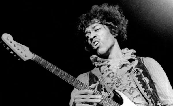 A black and white image capturing Jimi Hendrix's expressive performance with guitar.