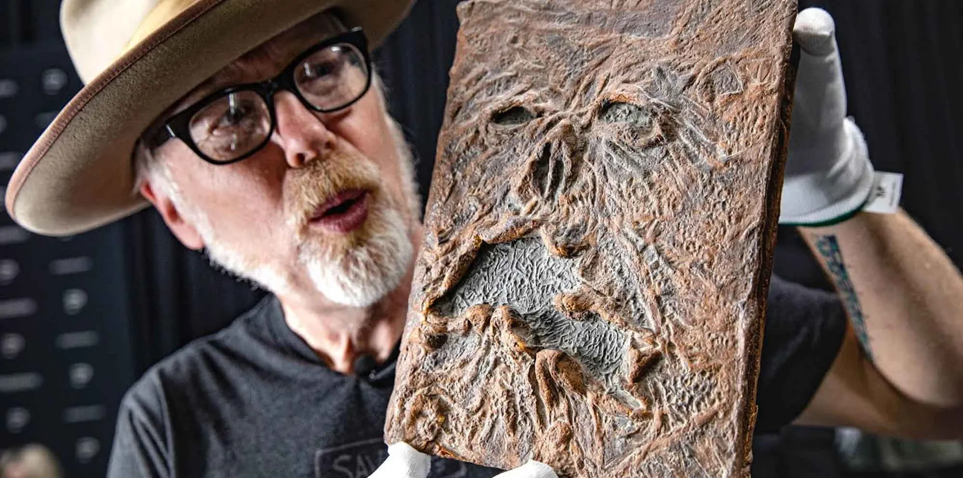 An expert holds a detailed dinosaur fossil with intricate carvings and realistic textures, showcasing ancient history and paleontology.