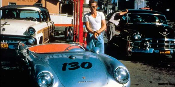 Retro sports car parked among classic cars and street scene in urban setting.