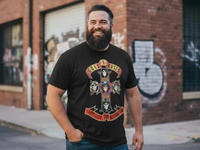 Lively man wearing Guns N' Roses band tee with skull design, standing outdoors in front of graffiti wall, showcasing rock band merchandise.