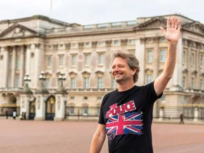 British man waving outdoors in front of a historic government building showing support for the UK police with a graphic t-shirt.