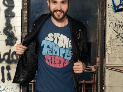 Bold man wearing a "Stop the Hate" graphic t-shirt and leather jacket in front of graffiti-covered walls.